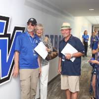 Guests standing against a wall the Jamie Hosford Football Center dedication.